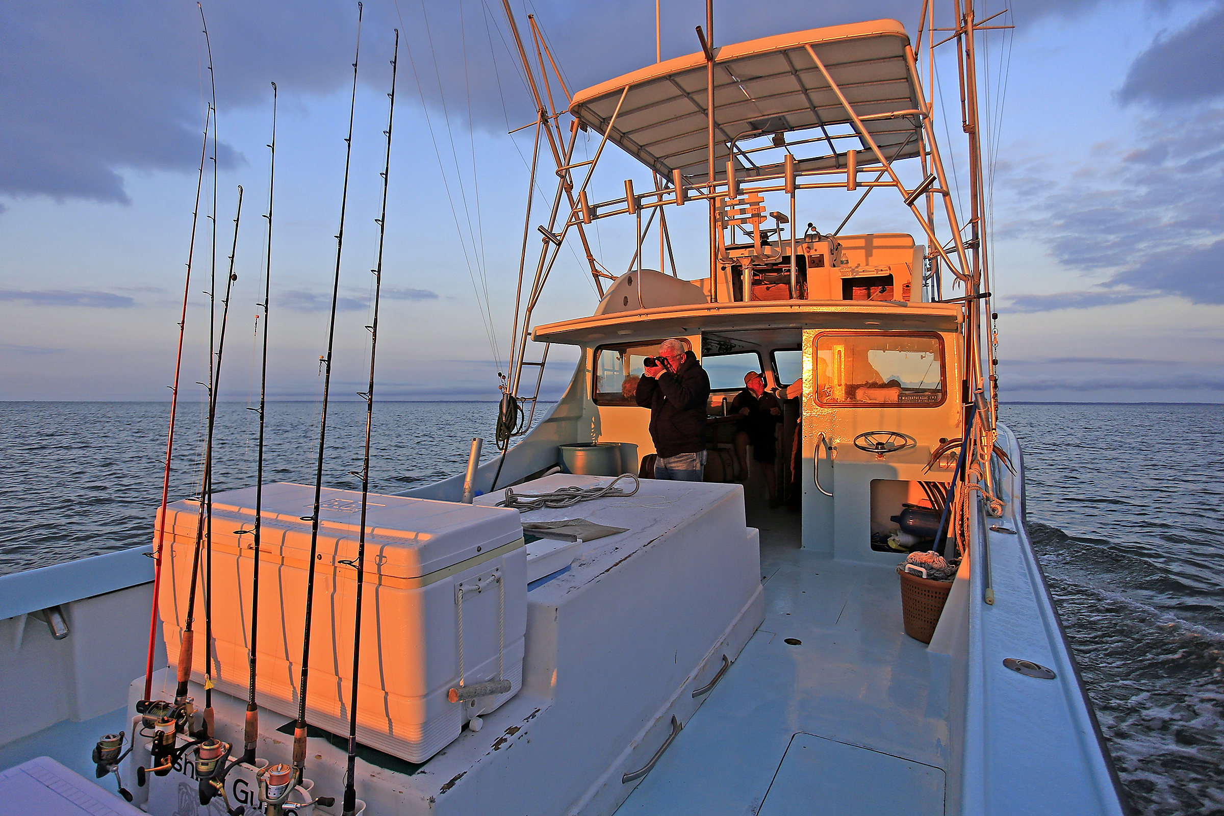 The Class Act deck at golden hour, rods lined up in the rack, the Captain at the helm