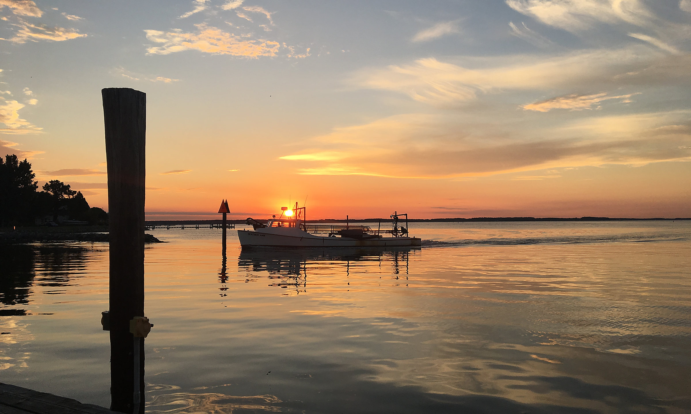 Sunset over the dock pilings, a workboat heading in