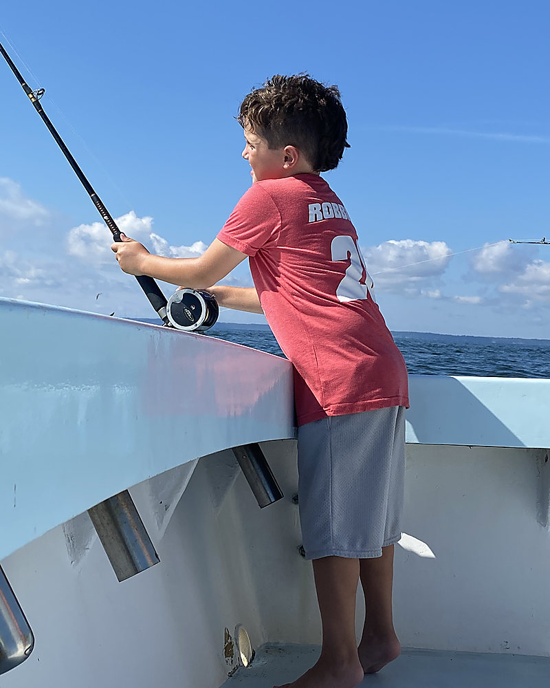 A boy with a trolling rod at the rail