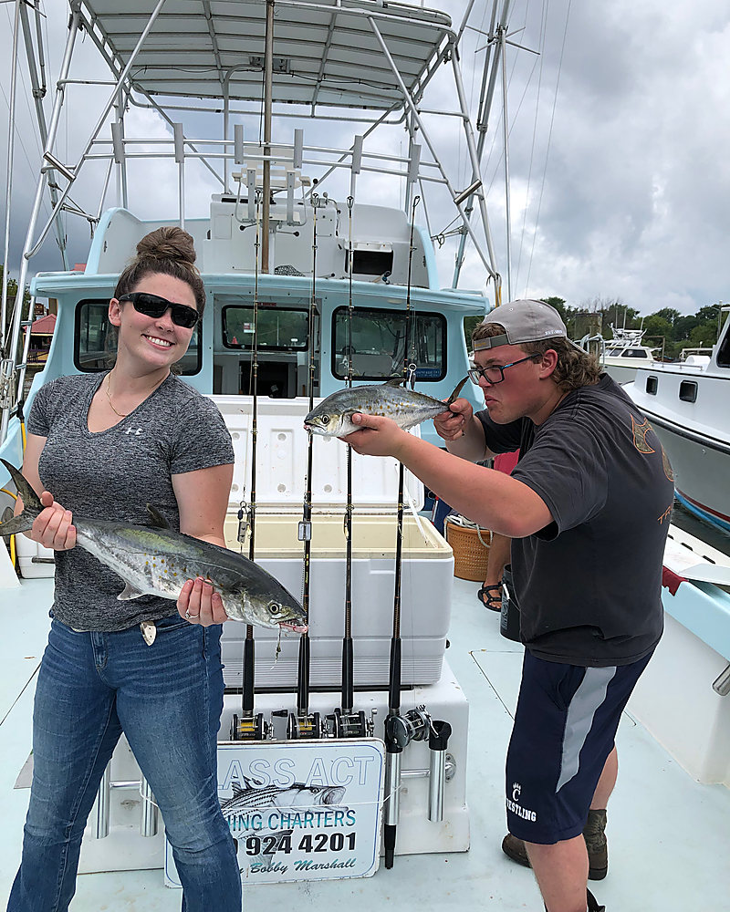 Two anglers on deck with their fish, the rod rack behind them