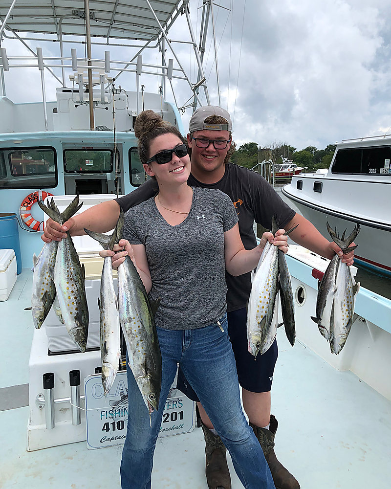 Two anglers each holding two fish, in front of the rod rack